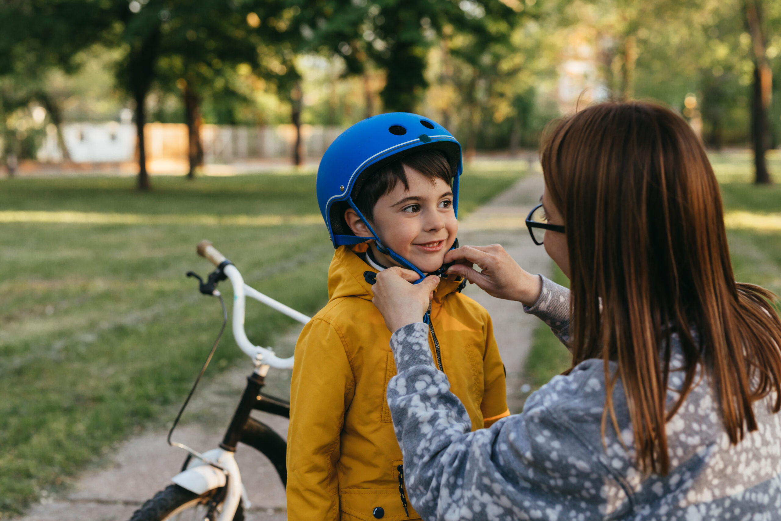 mother puts safety bike helmet on her sons head
